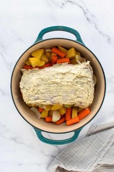 a pot filled with carrots, potatoes and hummus next to a napkin on the side