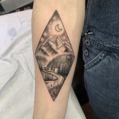 a person with a tattoo on their arm that has mountains and a river in it