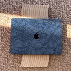 an apple laptop computer sitting on top of a wooden table next to a brown rug