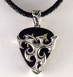 a black and white pendant with an ornate design on it's face, hanging from a leather cord