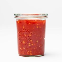 a jar filled with red sauce on top of a white table