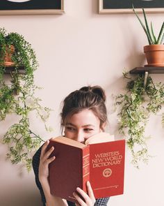 a woman holding a red book in front of her face