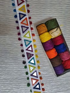 colorful yarn is in a box and next to it's string spools