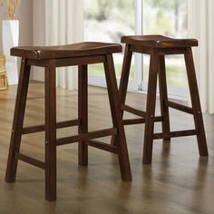 two wooden stools sitting on top of a hard wood floor next to a window