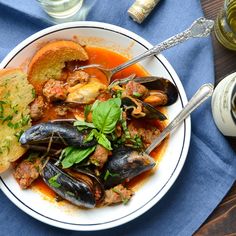 a white bowl filled with mussels on top of a table next to silverware