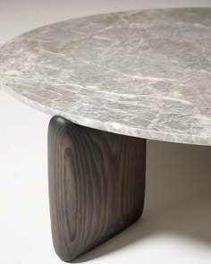 a white marble table with wooden legs on a white surface, viewed from the top