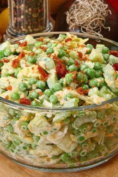 a bowl filled with pasta and peas on top of a wooden table next to other food items