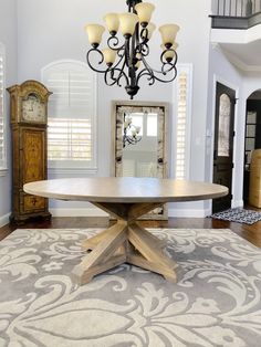 a chandelier hangs from the ceiling above a round wooden table