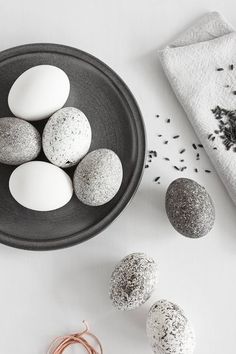 some white and black speckled eggs in a bowl next to two other balls on a table