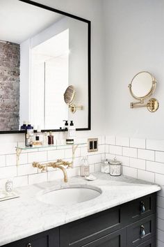 a bathroom sink sitting under a mirror next to a wall mounted faucet in a bathroom