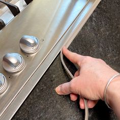 a hand is pointing at the knobs on an oven