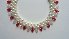 a white necklace with red and white pearls on it's sides, surrounded by crystal stones