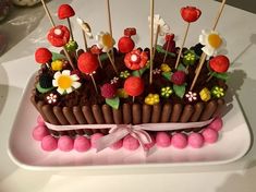 there is a cake decorated with flowers and candy on the plate, as well as strawberries