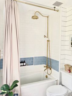 a bathroom with blue and white tiles on the walls, tub, shower head, toilet and sink