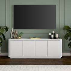 a living room with green walls and a large tv on top of a white cabinet