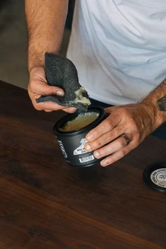 a man with his hands on a can of food and a black glove holding something in it