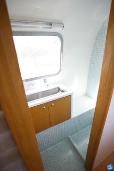 the inside of a bathroom with a sink and window in it's side wall