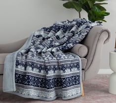 a blue and white blanket sitting on top of a couch next to a plant in a living room