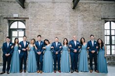 a group of people standing next to each other in front of a brick wall with windows