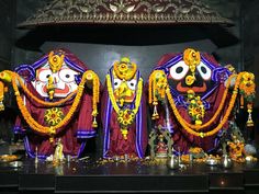 three colorfully dressed deities in front of a shrine