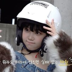 a girl wearing a white helmet and holding her hand up to her face while looking at the camera