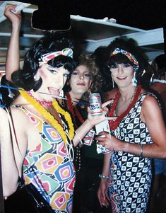 three women dressed up in costumes posing for the camera with one holding a can of soda