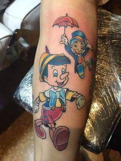 a cartoon tattoo on the arm of a person with an umbrella and two other characters