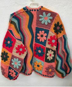 a colorful crocheted jacket hanging on a wall