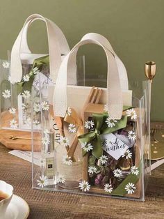 two clear bags with white flowers on them sitting on a table next to a cup and saucer