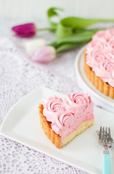 a piece of cake with pink frosting on a plate next to a knife and fork