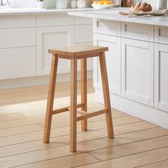 a wooden stool in a kitchen next to a counter with food on it and an open window