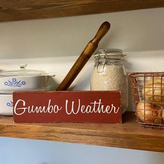 a wooden sign that says gumbo weather sitting on a shelf next to other items