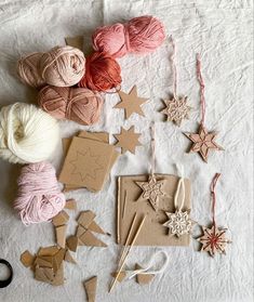 various crafting supplies are laid out on a white tablecloth, including balls of yarn and wooden stars