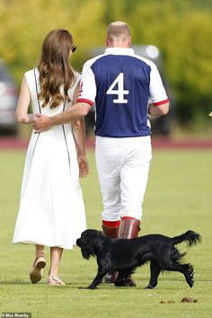 a man and woman walking with a dog on a field