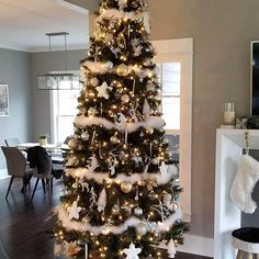 a decorated christmas tree in the middle of a living room with white and gold decorations