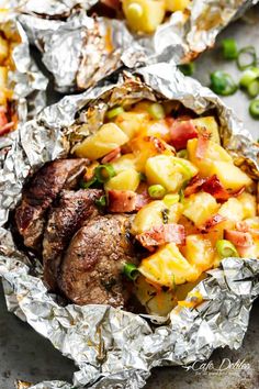 some food that is sitting in foil on top of a table with peas and pineapples