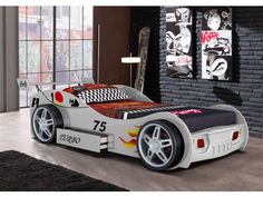 a red race car bed sitting in front of a brick wall