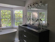 a bathroom with a tub, sink and large windows