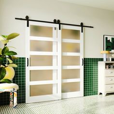 a kitchen with green tile and white cabinets, two sliding glass doors on the wall