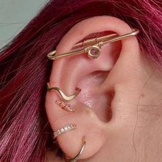 a woman with pink hair has three piercings on her ear