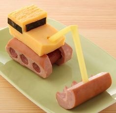 a green plate topped with a piece of food and a toy truck on top of it