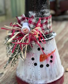 a snowman decoration on top of a red and white cone with a black pole in the background