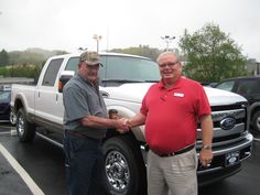 two men shaking hands in front of a truck