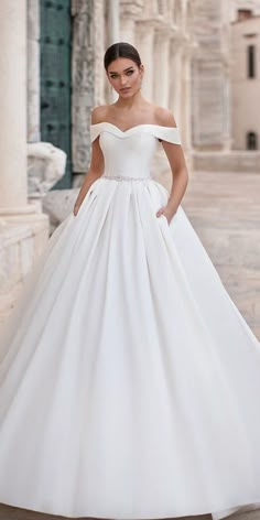 a woman in a white wedding dress posing for the camera with her hands on her hips