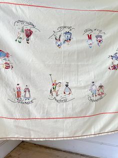 an old white cloth with embroidered pictures on it