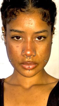 a close up of a person with piercings on her nose and nose ring in front of the camera