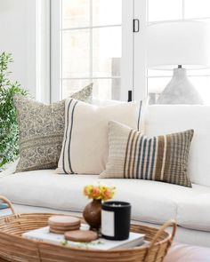 a living room filled with furniture and pillows on top of a white couch next to a potted plant