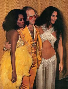 two women and a man dressed in costume posing for a photo with one woman wearing a yellow outfit