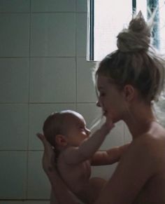 a woman is holding a baby in the bathtub