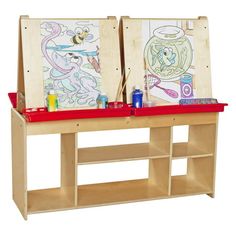 two children's art easels sitting on top of a wooden shelf with paint and pencils